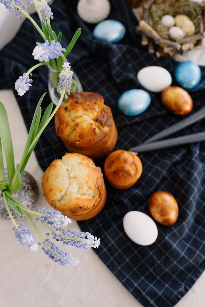A festive Easter setup with muffins and painted eggs on a table.